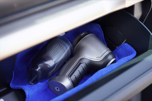 EZVac Pro and its clear dust container stored inside a car glove compartment